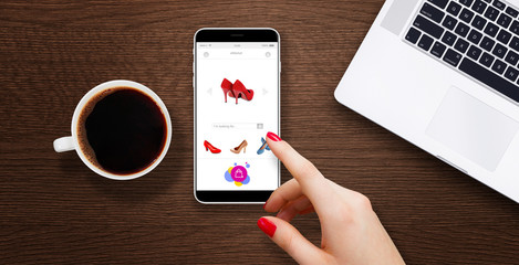 Wall Mural - Women shopping shoes on internet. Smartphone on wooden table beside cup of coffe and laptop