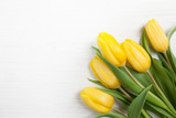 Fototapeta Tulipany - Yellow tulips on white wood background. Spring - poster with free text space.