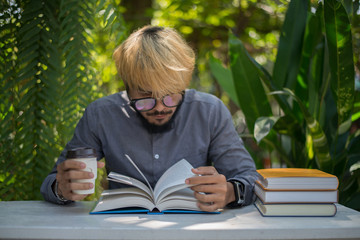 Wall Mural - Young hipster beard man drinking coffee while reading books in home garden with nature. Education concept.