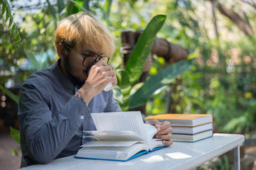 Wall Mural - Young hipster beard man drinking coffee while reading books in home garden with nature. Education concept.