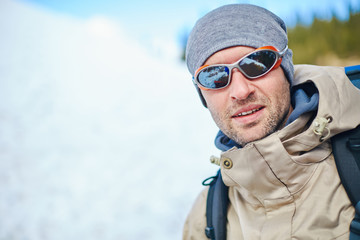 Wall Mural - closeup portrait of hiker in sunglasses with backpack against the snow in the Carpathians mountains at winter