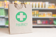 Recycled paper bag with a green Pharmacy logo in a drugstore. Empty copy space for Editor's content.