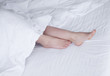 © lashkhidzetim - Bare legs of a young woman sleeping in her bed at home. Focus on legs.