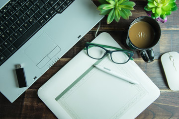 Top view of office stuff graphic design with pen mouse pad laptop wireless mouse and coffee cup on wooden table.Concept graphic design workplace.