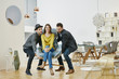 © Westend61 - Two man in furniture shop lifting woman sitting in wrapped arm chair