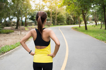 Wall Mural - Back view of young fitness woman running on the road in the morning. People and sport concept, Selective focus