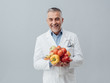 © stokkete - Smiling nutritionist holding fresh vegetables and fruit