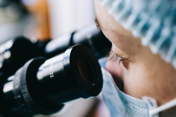 Wall Mural - close up view of scientist eye in glasses looking at microscope.