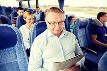 Poster - happy senior man reading newspaper in travel bus