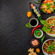 Asian food served on black stone, top view, space for text