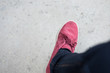 close up woman wearing  shoes with blue jean and standing on cement floor.