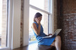 © Monkey Business - Businesswoman By Window Using Mobile Phone And Laptop