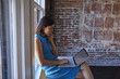 © Monkey Business - Businesswoman By Window Using Mobile Phone And Laptop