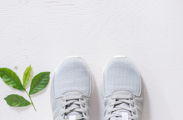 Close up clean running shoes and green leaf on rustic wood.