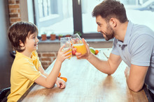 Side View Of Happy Father And Son Drinking Fresh Juice Together