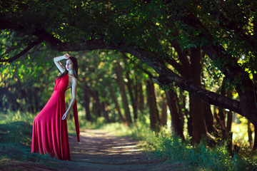 Wall Mural - Photo of fashion sexy woman in red dress in fairy forest. Beauty springtime