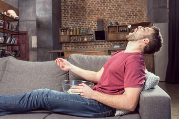 man eating popcorn while watching movie at home