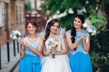Canvas Print - The bride with bridesmaids keep bouquets and stand in the street