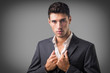 © theartofphoto - Young businessman confidently posing in front of camera, wearing business suit without neck-tie, with shirt open on neck, on dark background