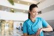 beautiful woman doctor or nurse standing in a hospital lobby checking the time with her wristwatch