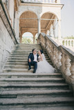 Fototapeta Na drzwi - beautiful and young bride and groom sitting on the stairs