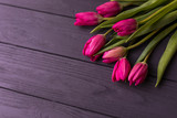 Fototapeta Tulipany - Pink tulips on the black background. Flat lay, top view. purple easter tulips arrangement with space for text