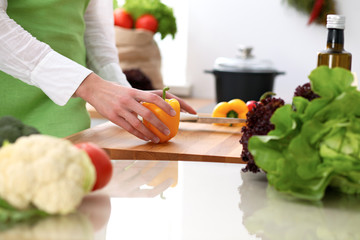 Closeup of human hands cooking vegetables salad in kitchen on the glassr table with reflection. Healthy meal and vegetarian concept