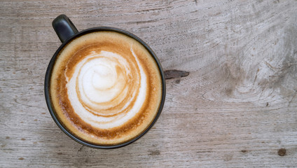 Top view of hot coffee latte cappuccion spiral foam on wood table