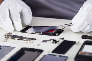 Repairman Disassembling Smartphone With Tweezers