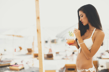 Wall Mural - Young woman with coctail on the beach at summer