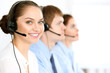 © rogerphoto - Call center operators. Focus at brunette business woman in headset