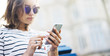 Hipster texting message on smartphone or technology, mockup of blank screen. Girl using cellphone on building castle background close. Tourist female hands holding gadget on blurred summer backdrop