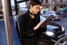 Horizontal Shot Of Young Woman Riding A Public Transport And Browsing The Tablet.