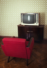 Wall Mural - Vintage room with old fashioned red armchair and retro tv over obsolete wallpaper, image toned.