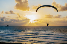 Silhouette Of Unrecognizable Person Flying On Parachute Over The Sea 