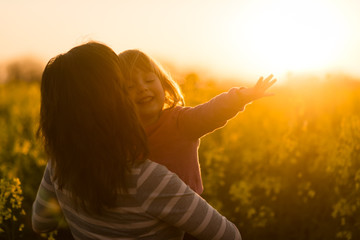 Woman holding cute smiling carefree girl child and facing away