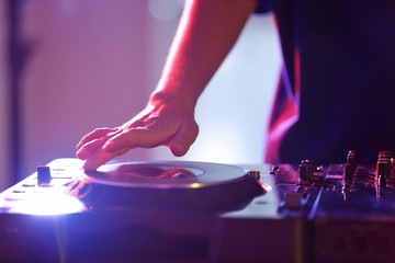 DJ mixing tracks on a mixer in a nightclub