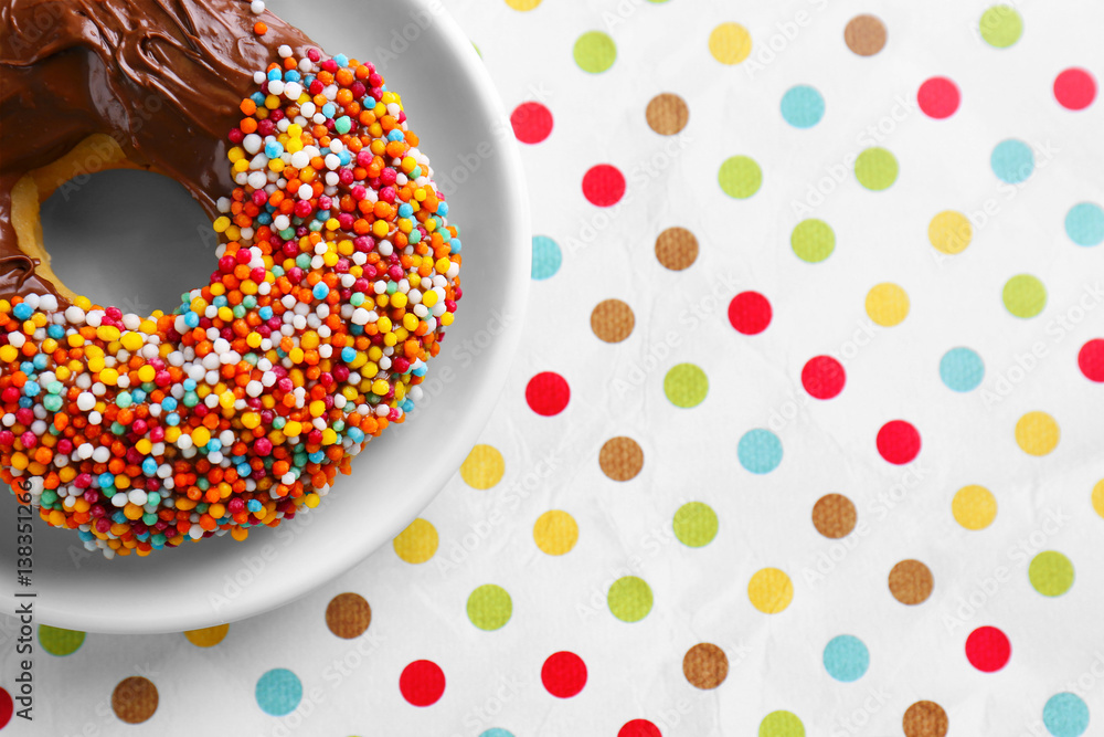 Plate with tasty glazed donut on colorful background