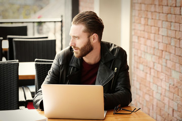 Handsome young man working on laptop at cafe