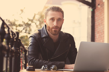 Handsome young man working on laptop at cafe