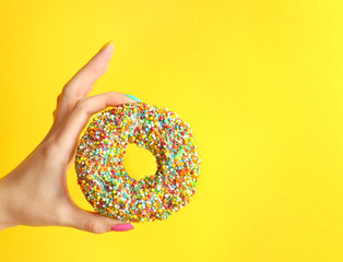 Wall Mural - Woman holding delicious donut on color  background