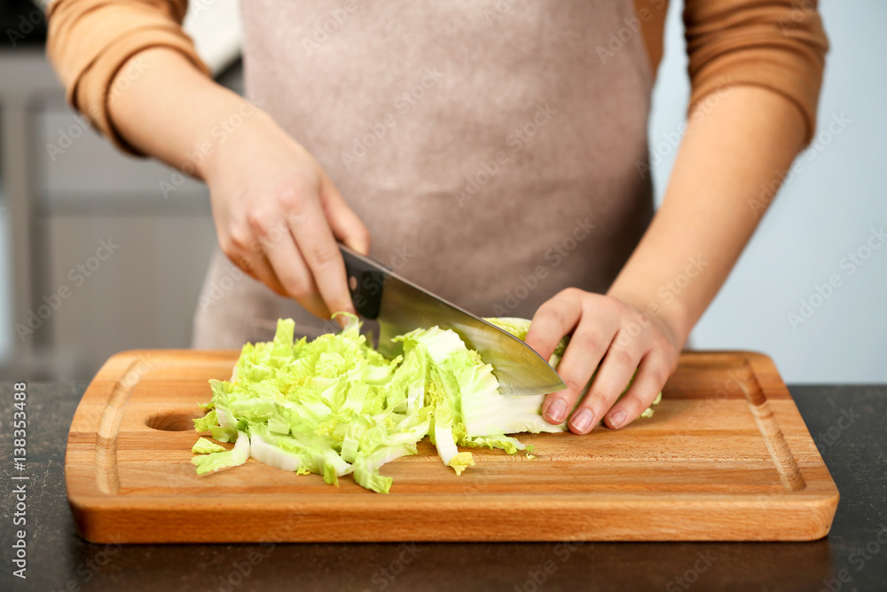 Female hands cutting Chinese cabbage at table in kitchen
