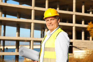 Wall Mural - Senior engineer with drawing standing against unfinished building