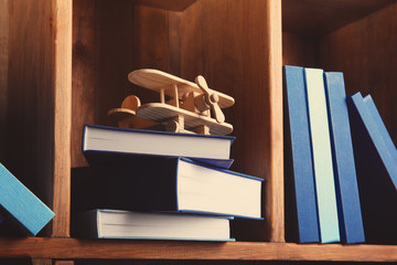 Poster - Stack of books with airplane on wooden shelf