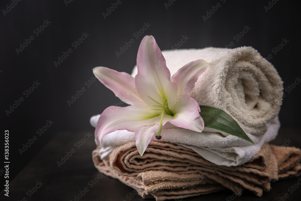 Beautiful spa composition with towels and lily flower on dark background