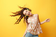 © Africa Studio - Beautiful young woman in headphones listening to music and dancing on yellow background