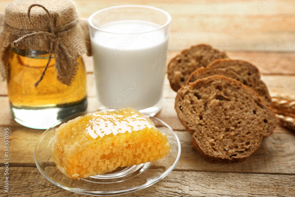Composition with milk, honey, bread and honeycomb on wooden background