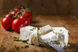 Feta cheese with knife and bunch of cherry tomatoes in background