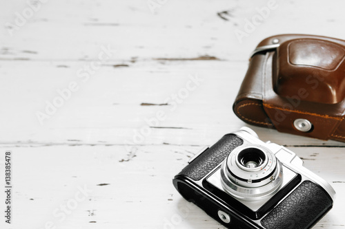 Stampe Old film camera in brown vintage case on white wood background