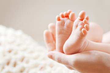 baby feet in mother hands. tiny newborn baby's feet on female shaped hands closeup. mom and her chil
